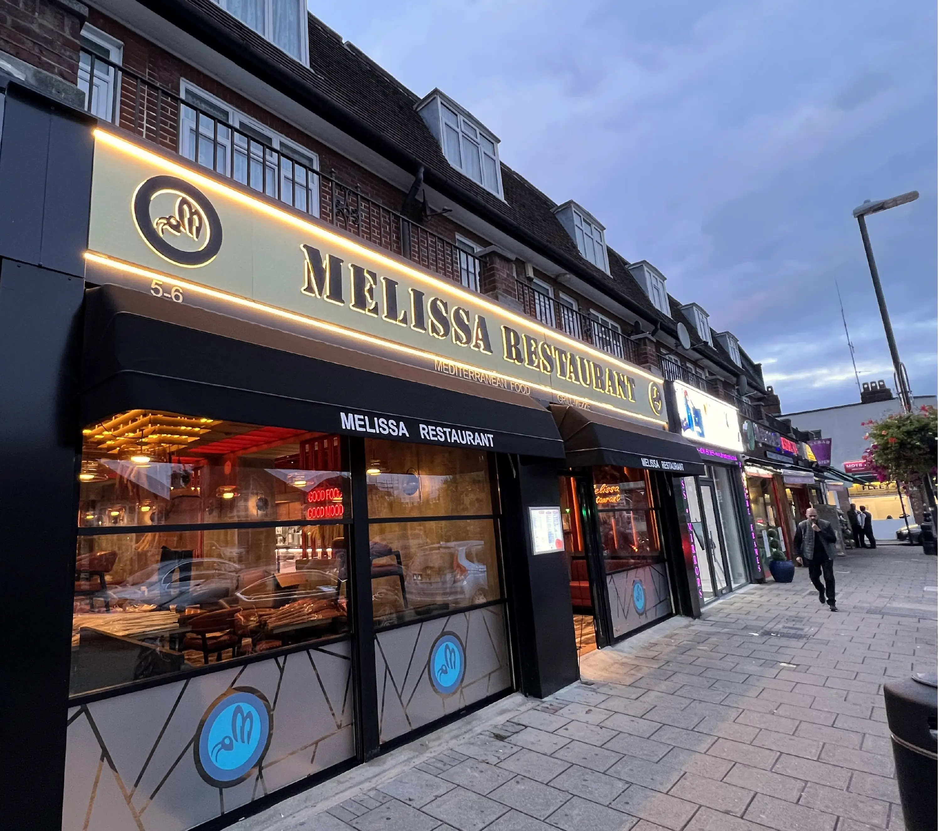 Halo-lit letters reading MELISSA RESTAURANT on a restaurant fascia in Canons Park at dusk
