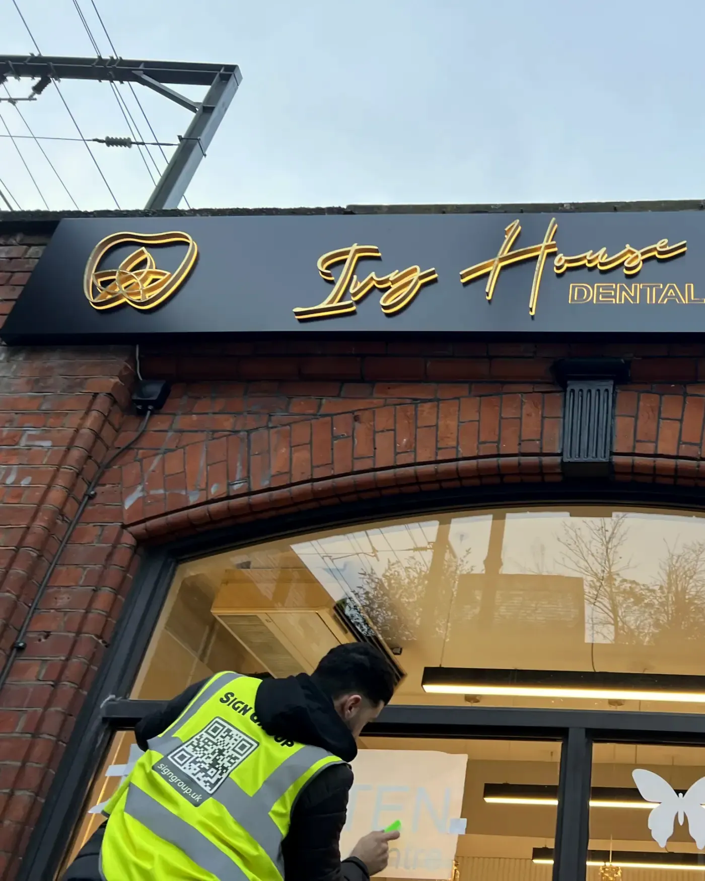 Sign Group fitter applying window graphics at Ivy House Dental, Camden