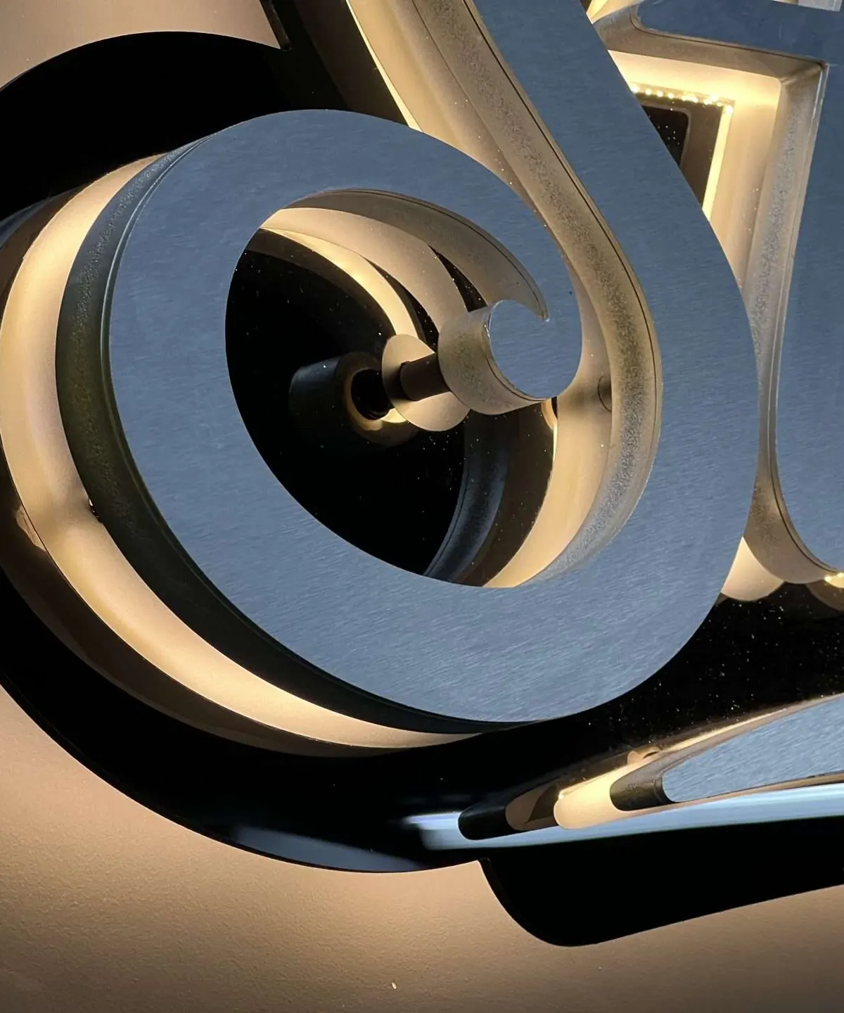 Close-up of the Studio B letters: brushed faces built up over an acrylic layer that carries the light