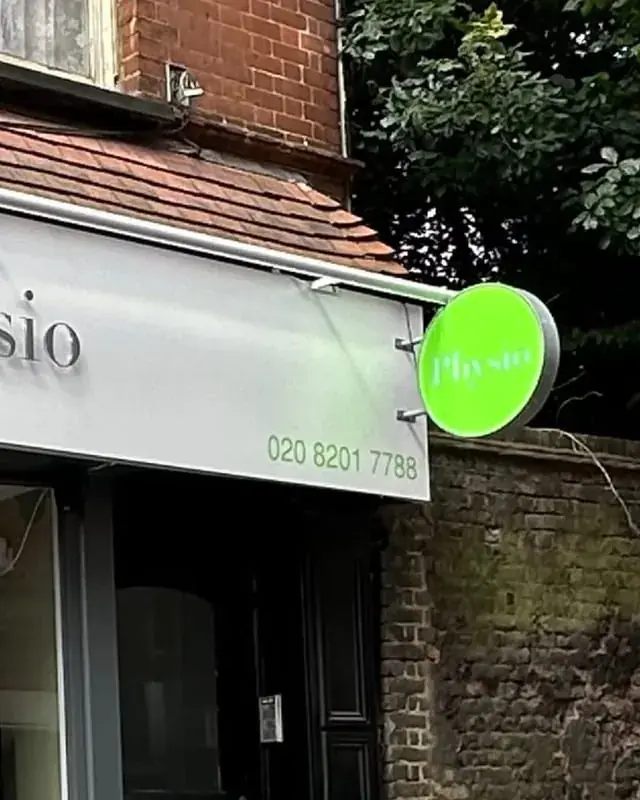 Round green projecting sign at the end of the Boost Physio fascia in Hampstead