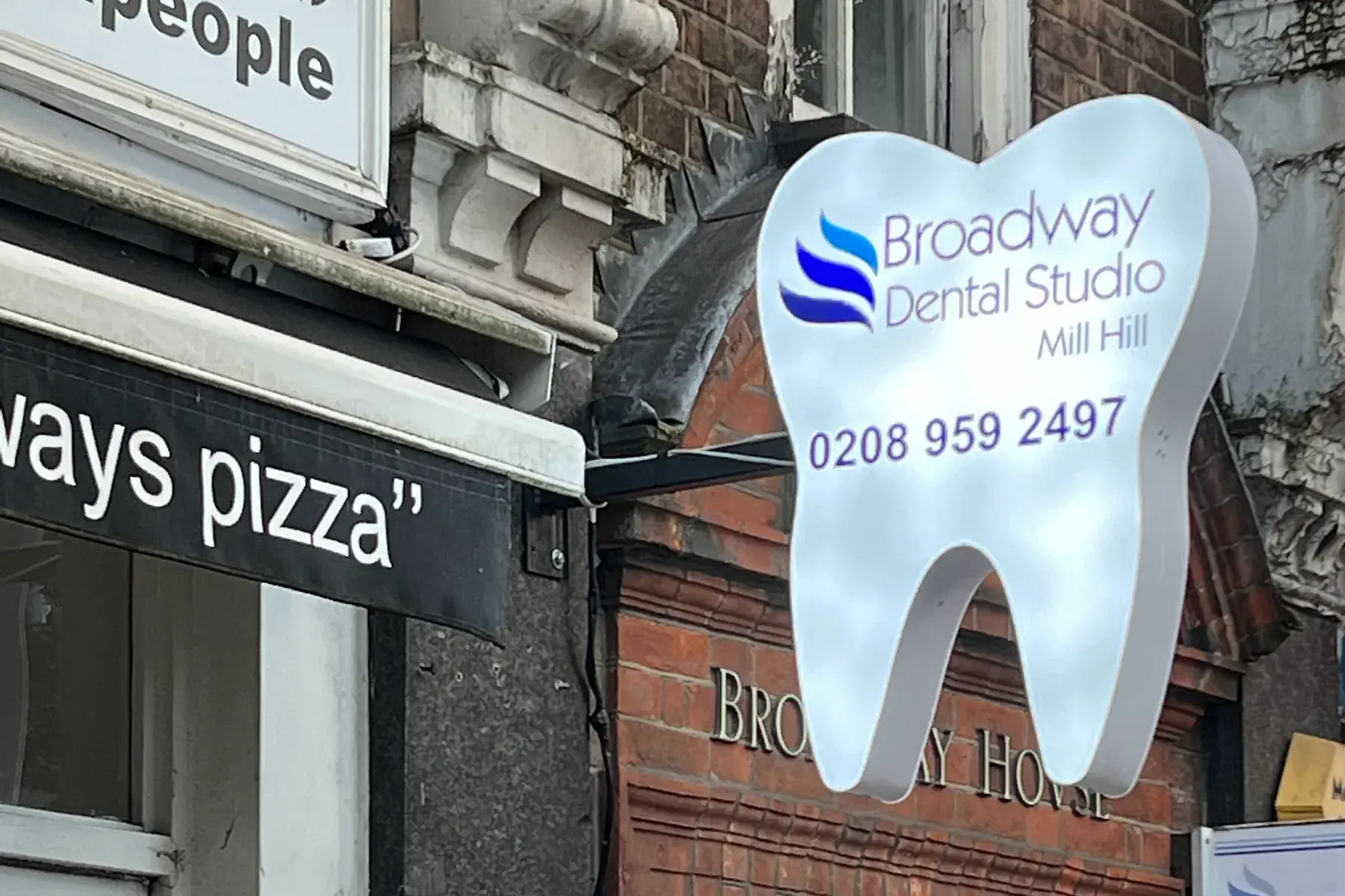 Close-up of the tooth-shaped projecting sign at Broadway Dental Studio, Mill Hill