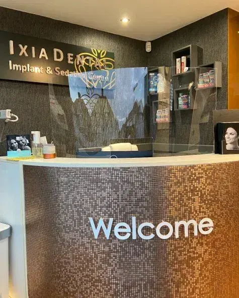 Ixia Dental reception: raised letters on the wall behind the desk and Welcome lettering on its front