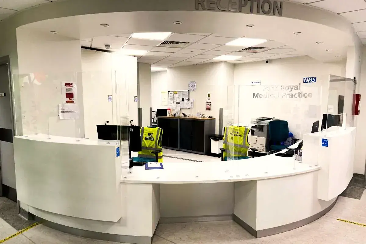 Reception desk at Park Royal Medical Practice with Reception lettering above it and wall signs behind