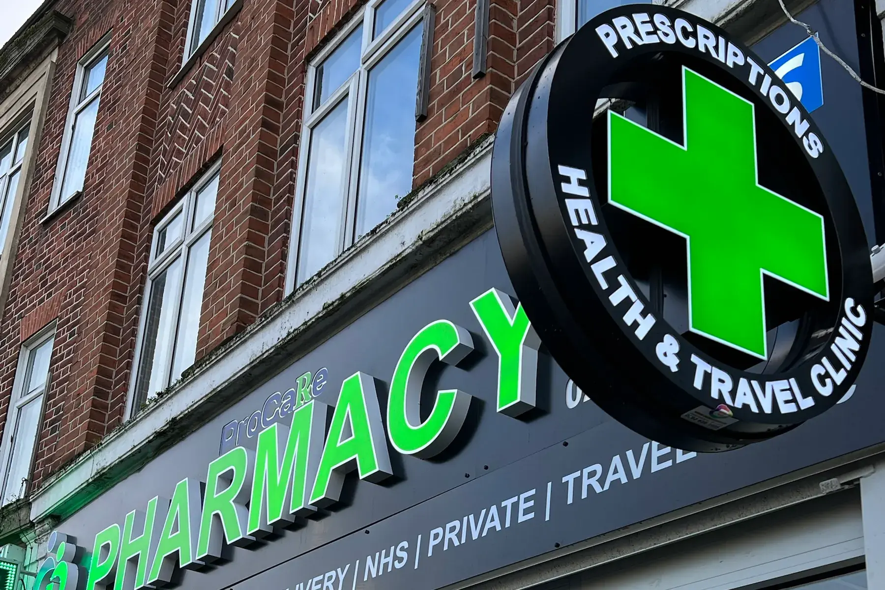ProCare Pharmacy fascia with built-up green letters and the round projecting cross sign above it