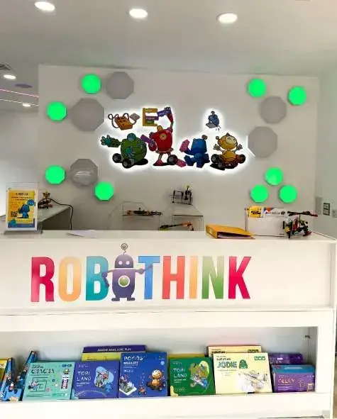 Robothink reception: coloured letters on the desk front and an illuminated character sign on the wall behind