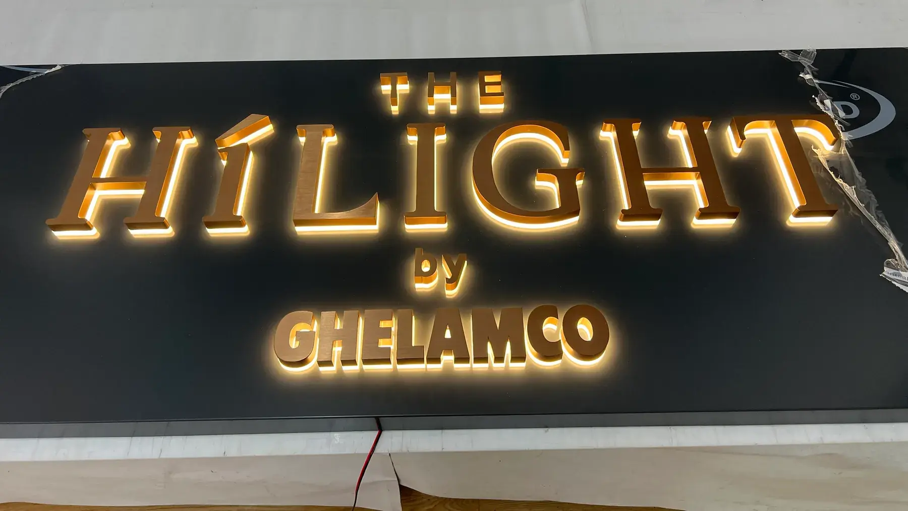 Halo-lit brushed rose gold stainless steel letters reading The Hilight by Ghelamco, switched on in the workshop