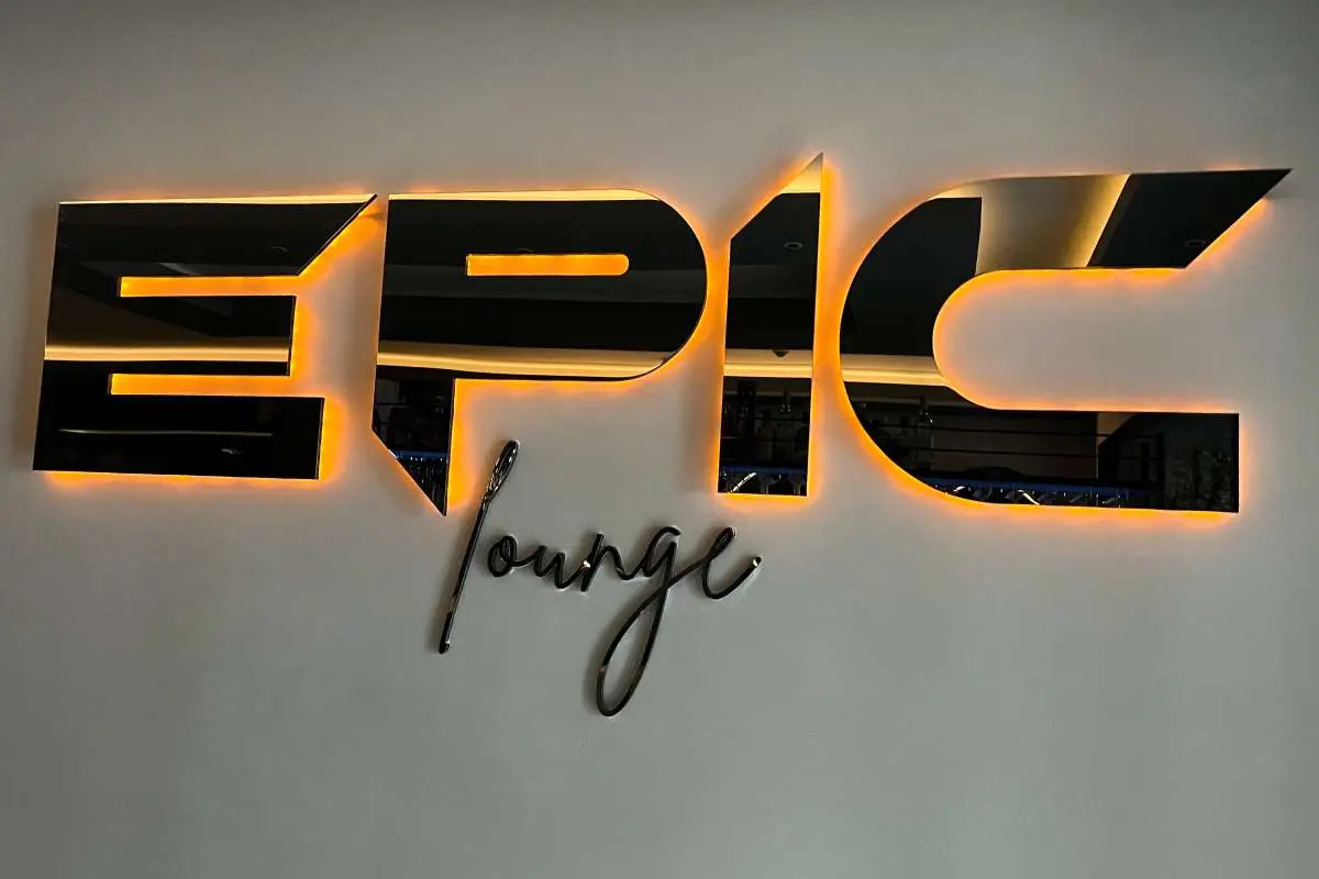 Black Epic Lounge letters with an orange halo on a grey wall