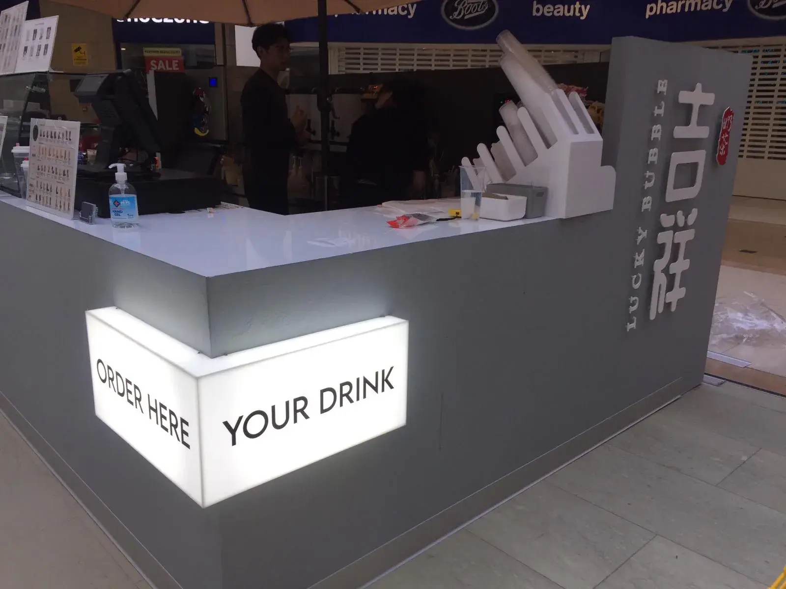 Lucky Bubble kiosk in a shopping centre with raised lettering on its side and an illuminated Order here lightbox on the corner