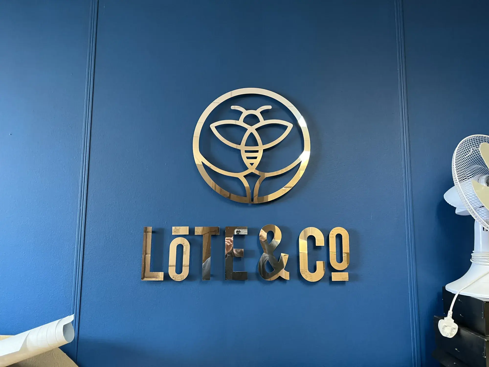 Gold Lote & Co logo and letters on a blue panelled wall